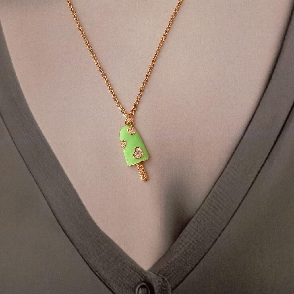 Este colgante con forma de paleta de helado en color verde, con pequeños corazones y cristales, es una pieza divertida que aporta ternura y delicadeza. Destaca y expresa tu estilo o con este colgante. ¡Luce audaz con este accesorio en cualquier atuendo!