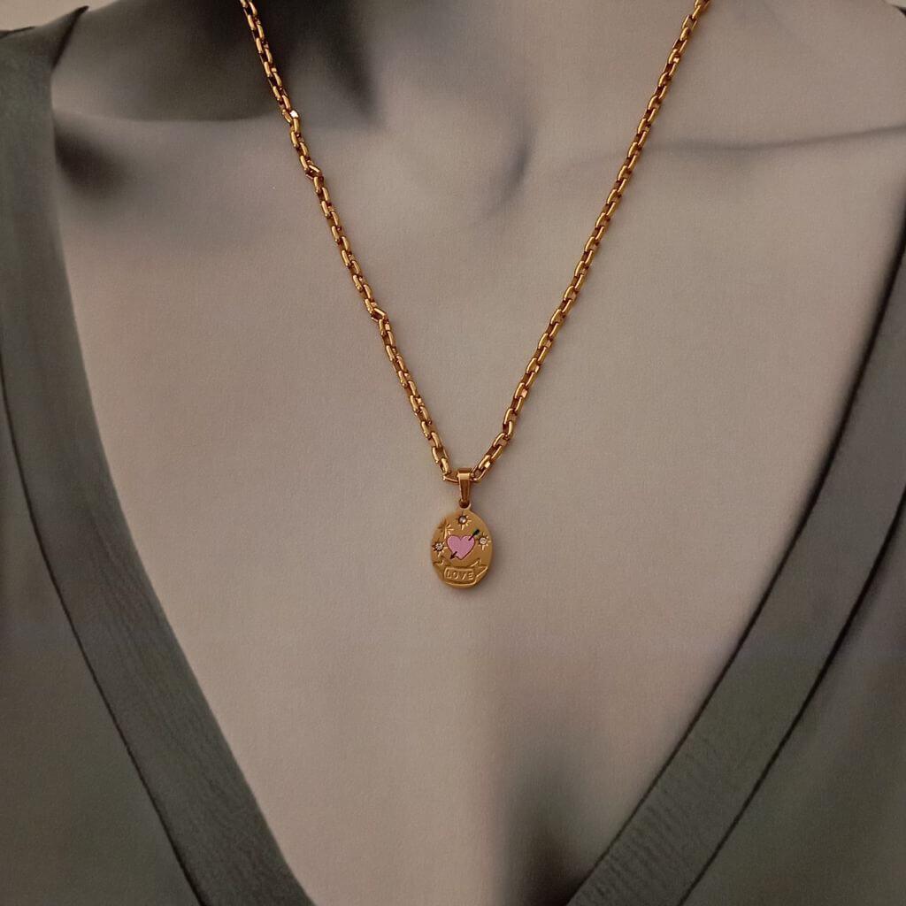 Este collar Corazón Rose Gold es una pieza elegante y sofisticada. Cuenta con un colgante en forma de medalla grabado con un corazón rosa y una flecha, adornado con pequeños brillantes. Con este collar, podrás lucir un look único y femenino.