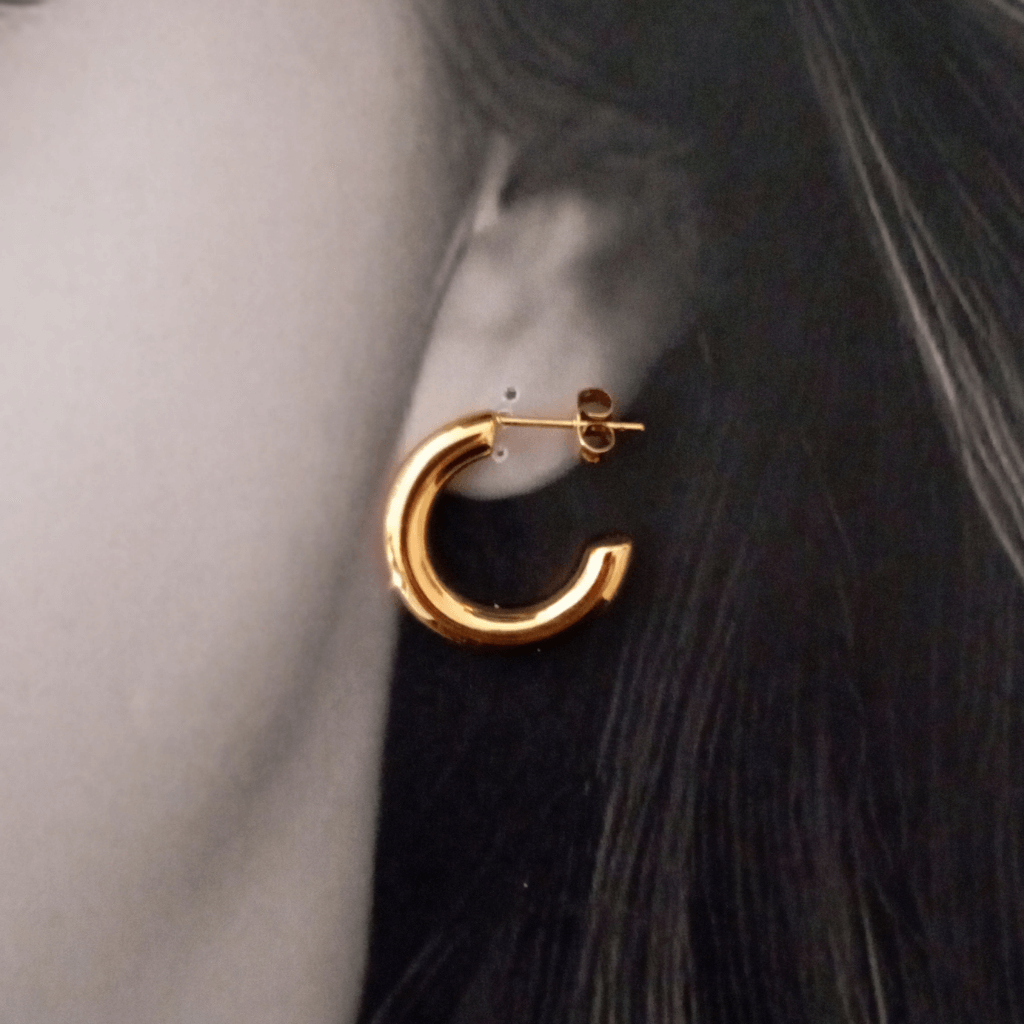Mujer vistiendo unos Imagen de pendientes de aro forma C gruesos