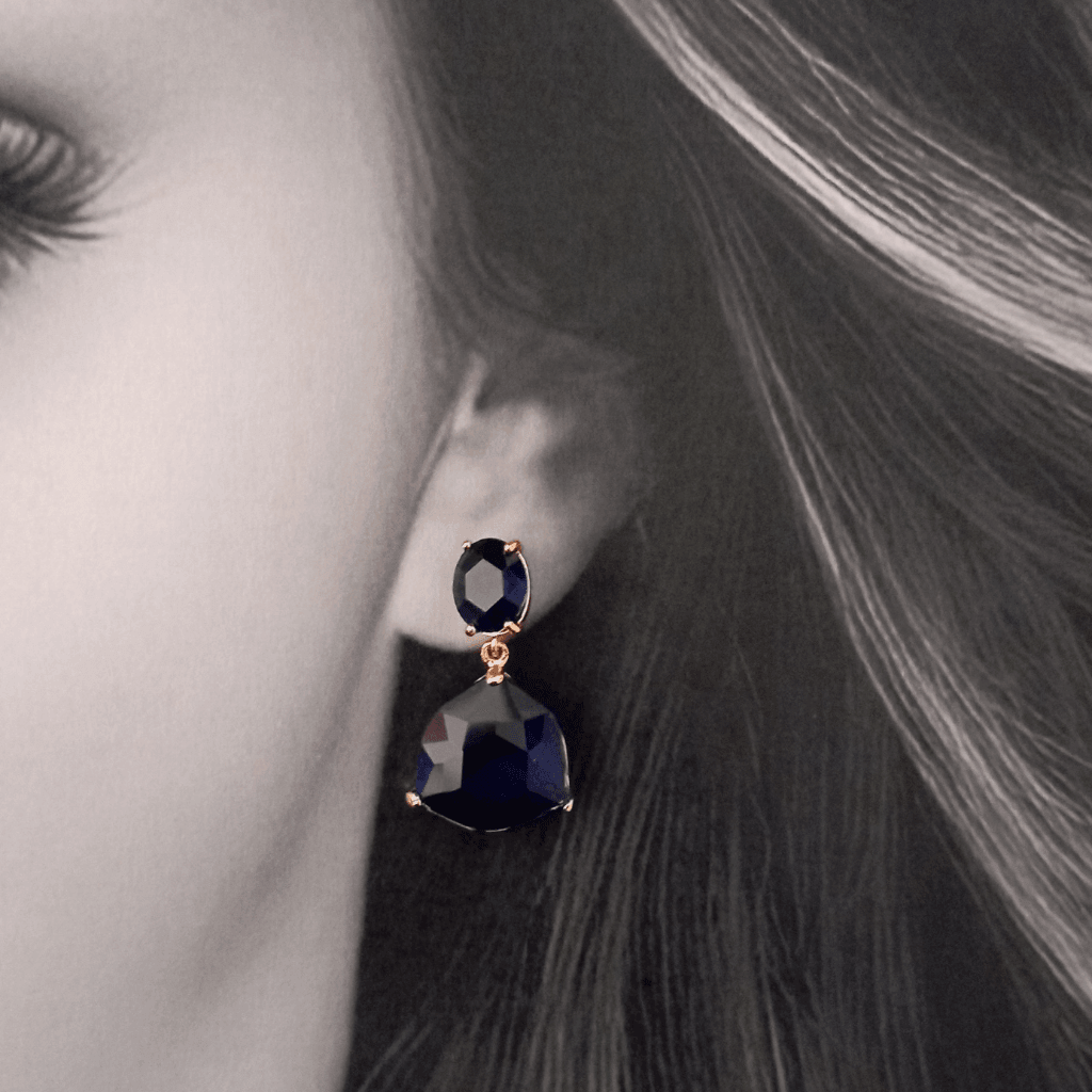 Mujer con pendientes de fiesta con cristal azul. El tono azul brillante evoca la belleza del cielo nocturno, mientras que el diseño sofisticado y moderno añade un toque de arte a tu atuendo. Perfectos para cualquier ocasión especial, estos pendientes son la definición del lujo.