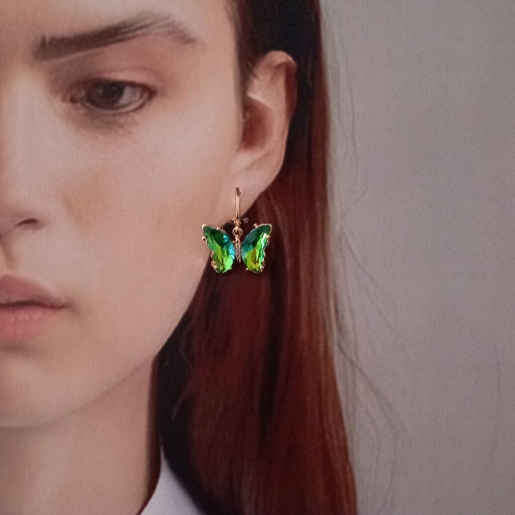 Estos elegantes pendientes en forma de mariposa cuentan con cristales verdes colgando de un mini aro. Con un toque de color y un diseño único, son perfectos para cualquier ocasión. Disfruta de su belleza y añade un toque de sofisticación a tu estilo.
