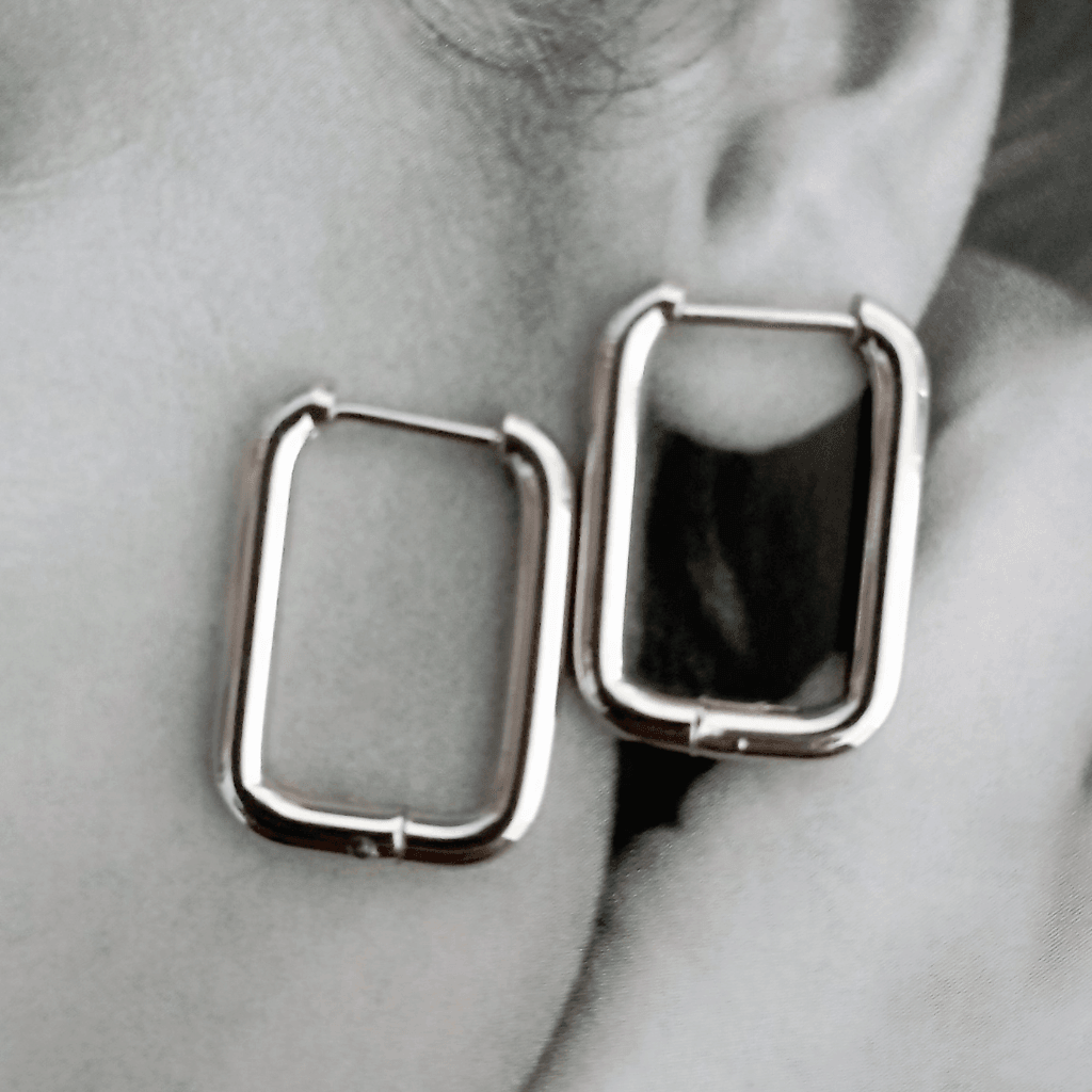 Pendientes Rectangulares Acero. Estos pendientes aros rectangulares de acero en color plateado son el accesorio perfecto para darle un toque de audacia y estilo a tus conjuntos. ¡Haz una declaración de moda con estos pendientes atrevidos!