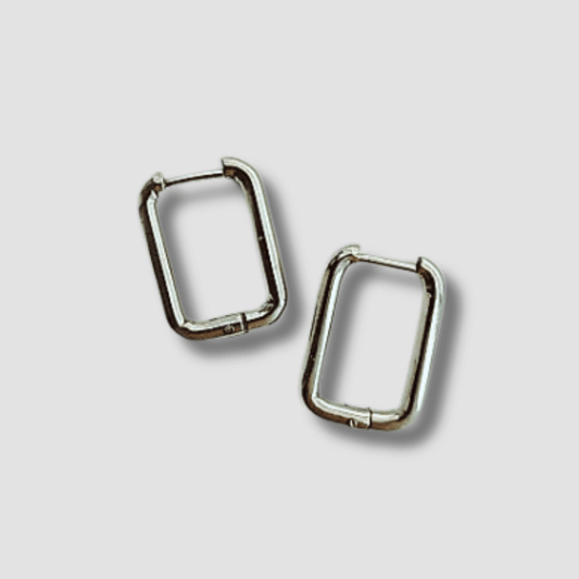 Pendientes Rectangulares Acero. Estos pendientes aros rectangulares de acero en color plateado son el accesorio perfecto para darle un toque de audacia y estilo a tus conjuntos. ¡Haz una declaración de moda con estos pendientes atrevidos!