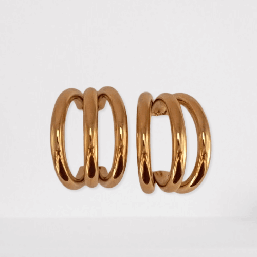Añade estos pendientes Triple aro acero oro a tu colección de accesorios. Con sus tres aros en uno, bañado en oro 14k y antialérgicos, darán a tus looks más casuales un toque sofisticado.