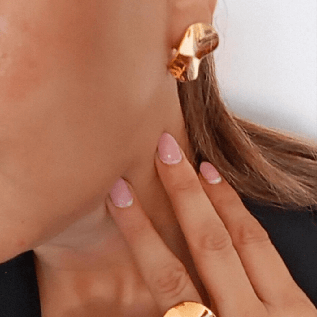 Mujer vistiendo pendiente Gema Irregulares tipo botón para oficina en Oro