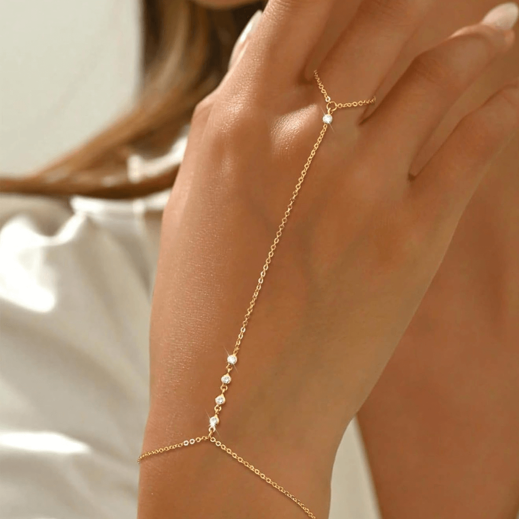 Mano femenina luciendo una pulsera de anillo con cadena dorada, ideal para verano o festivales