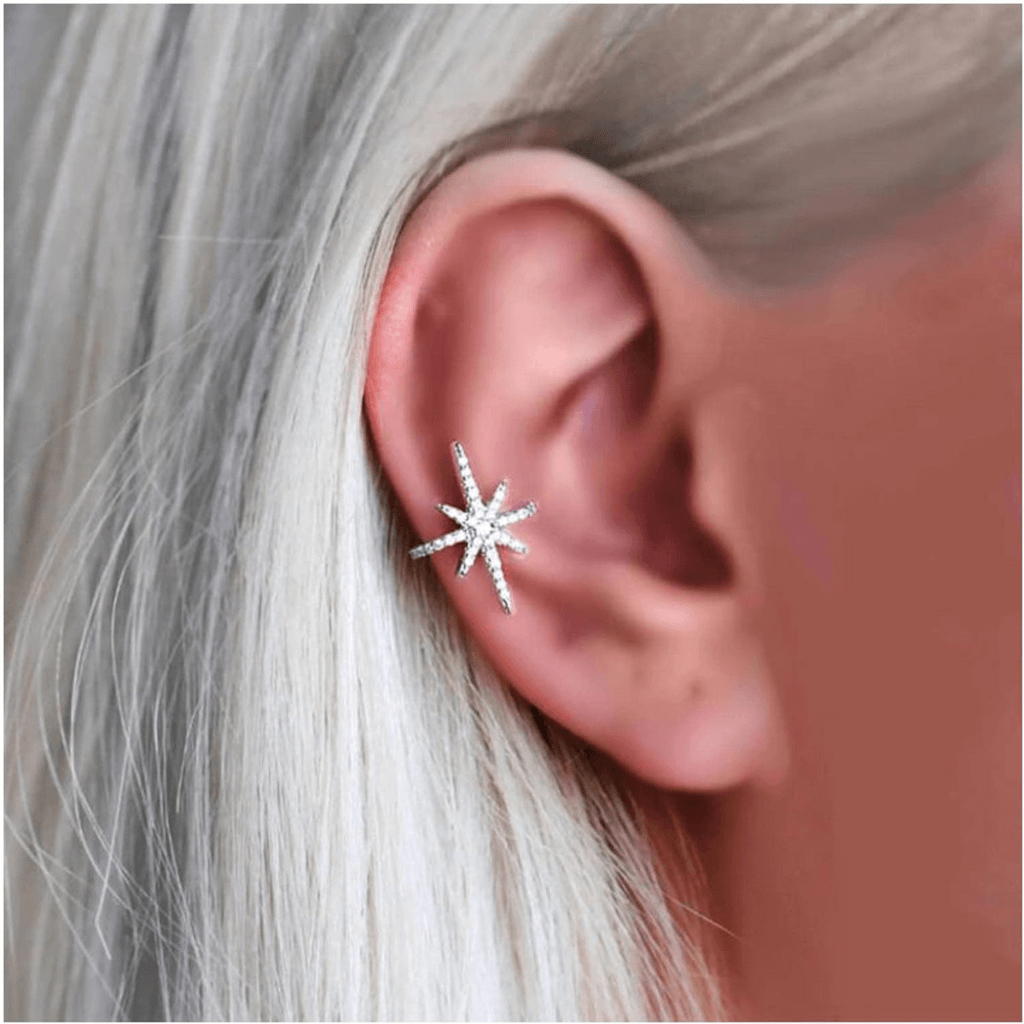 Pendientes ear cuff dorados brillando bajo el sol, combinados con un look de verano bohemio en un festival.