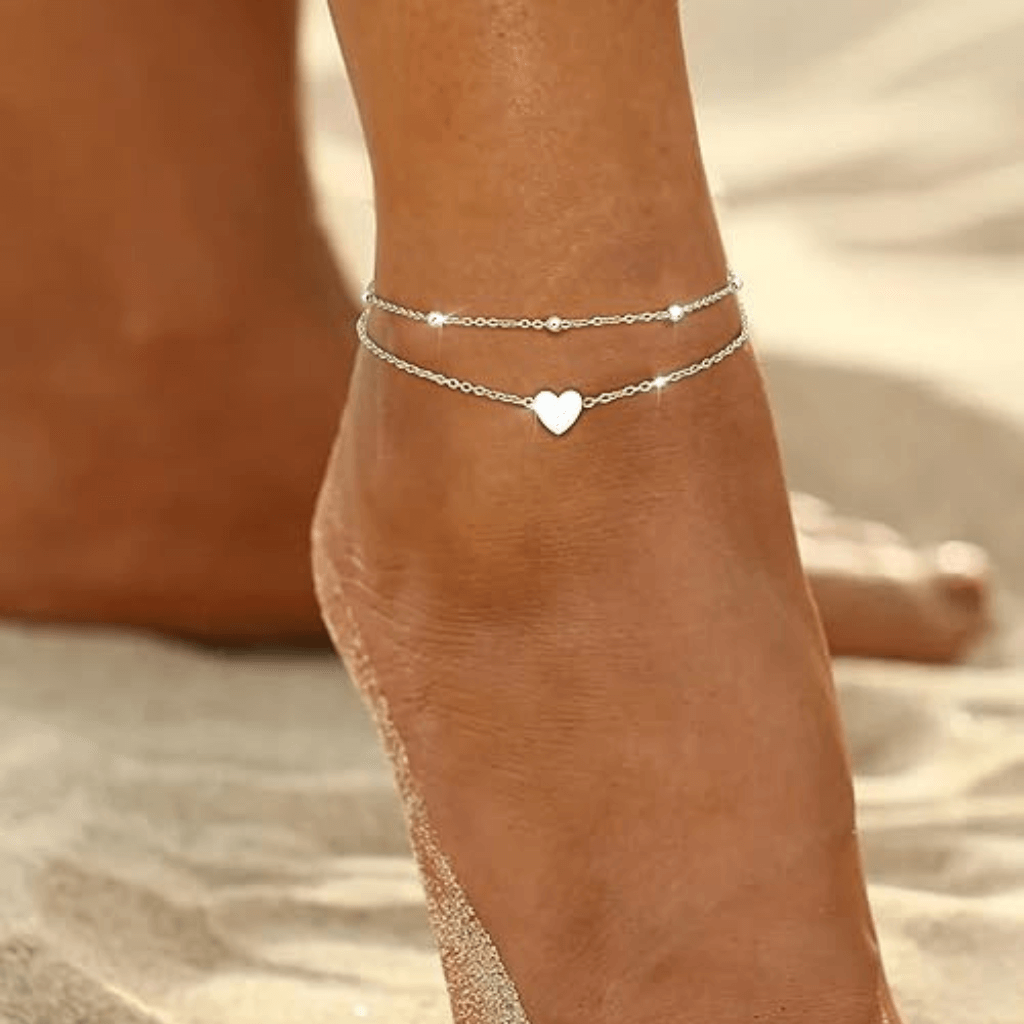 Pulsera tobillera de verano con dijes dorados sobre piel bronceada en la playa