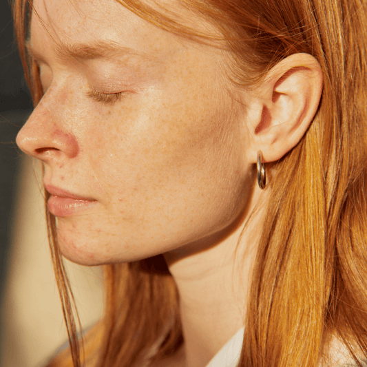 Imagen de mujer usando unos pendientes de aro dorados