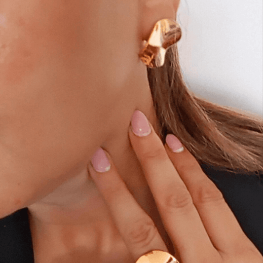 Juego de joyas de acero inoxidable con anillo y pendientes de diseño ondulado irregular en color dorado.