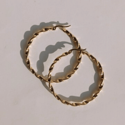 Imagen de Aros Pendientes Trenzados Maxi dorados en fondo rosa