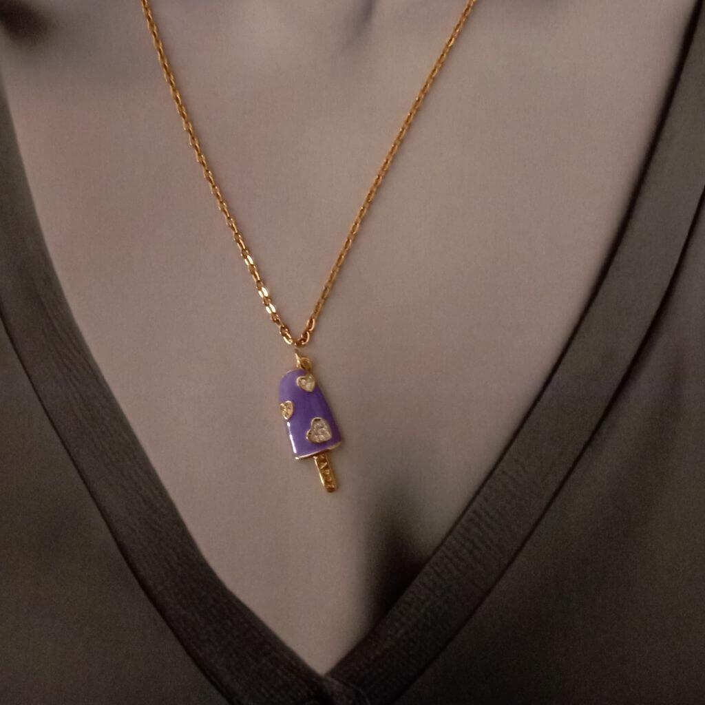 Colgante en forma de paleta de helado de color violeta y corazones chispeado de cristales es el accesorio perfecto para cualquier amante de la moda y la dulzura. Hecho con materiales de alta calidad. Es una pieza elegante y exclusiva que seguramente llamará la atención. Añade un toque de diversión y estilo simple y clásico a cualquier atuendo con este encantador colgante. 