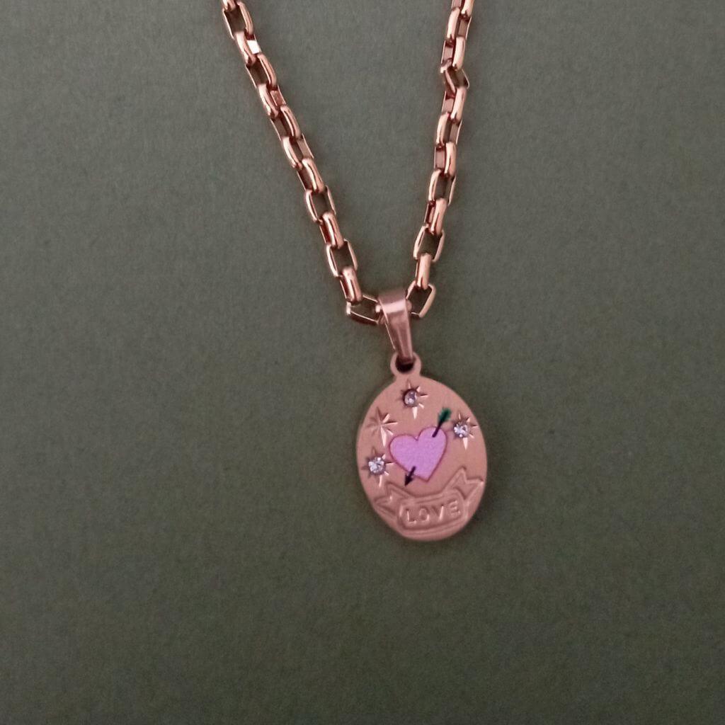 Este collar Corazón Rose Gold es una pieza elegante y sofisticada. Cuenta con un colgante en forma de medalla grabado con un corazón rosa y una flecha, adornado con pequeños brillantes. Con este collar, podrás lucir un look único y femenino. 