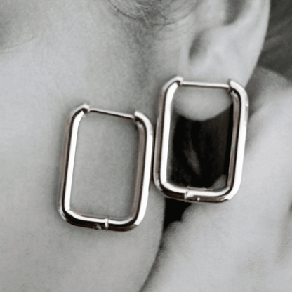 Pendientes Rectangulares Acero. Estos pendientes aros rectangulares de acero en color plateado son el accesorio perfecto para darle un toque de audacia y estilo a tus conjuntos. ¡Haz una declaración de moda con estos pendientes atrevidos! 