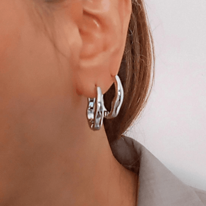 mujer vistiendo pendientes aro irregulares plateados
